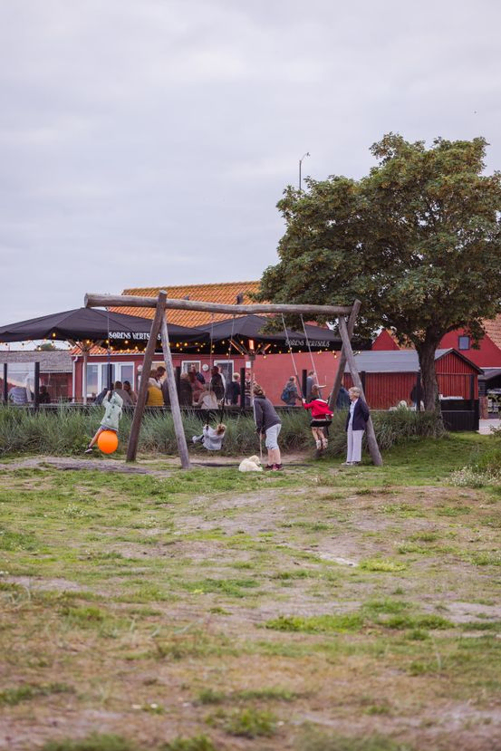 En af terrasserne ved Sørens Værtshus med udsigt til havet. Set fra havet. Der er gyngestativ til børn.