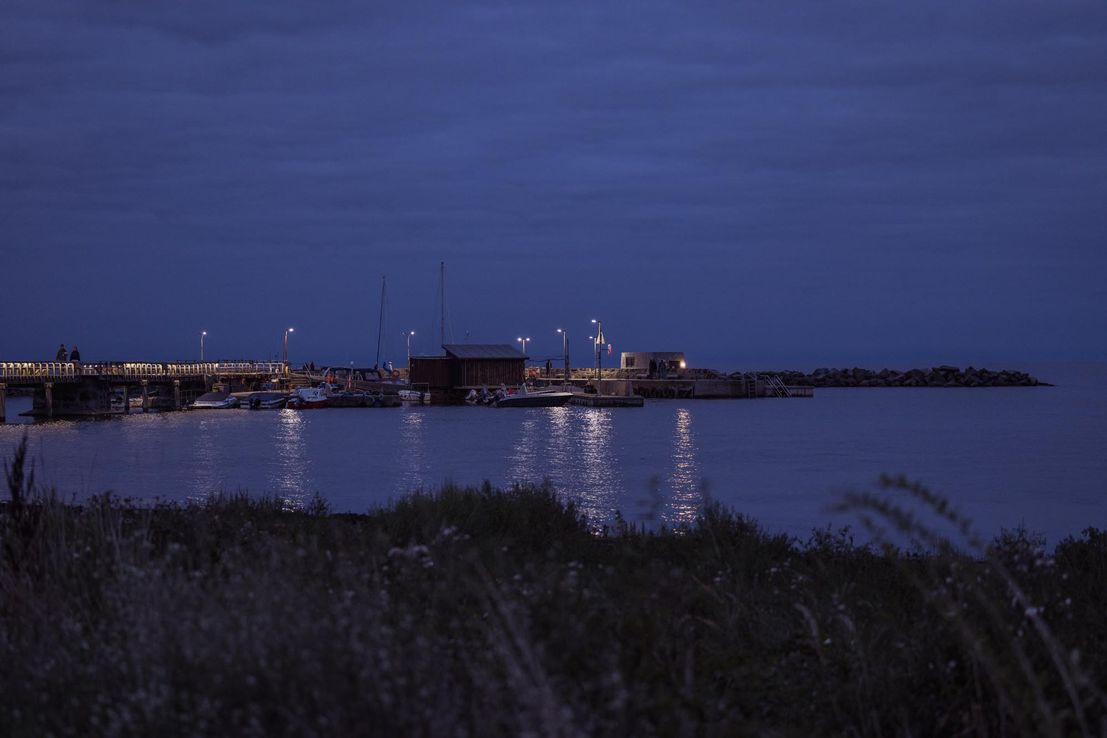 Aftenbelysning over Snogebæk Havn en sen sommeraften. Vandet er roligt og der er stilhed.
