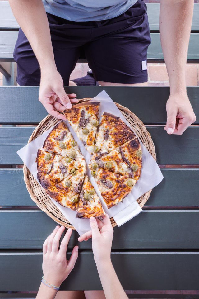 Pizza fra stenovn serveret i Snogebæk på Sørens Værtshus i Snogebæk. Par ses tage pizzastykker fra chili pizza.